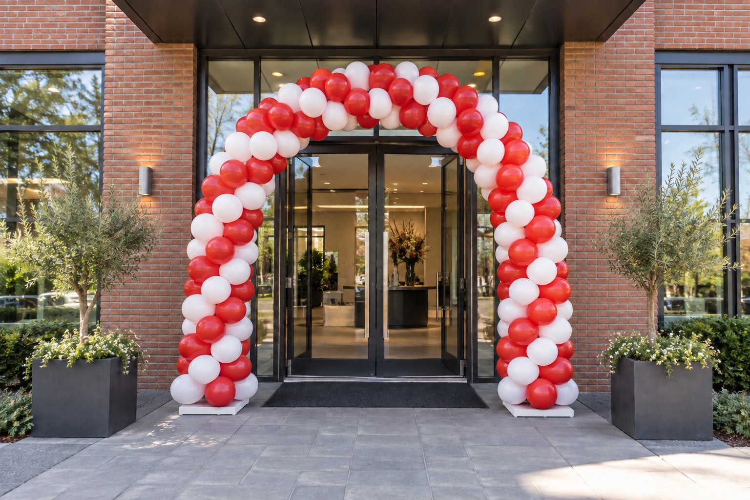 Rood-witte ballonnenboog op witte voetplaten bij een bedrijfsentree